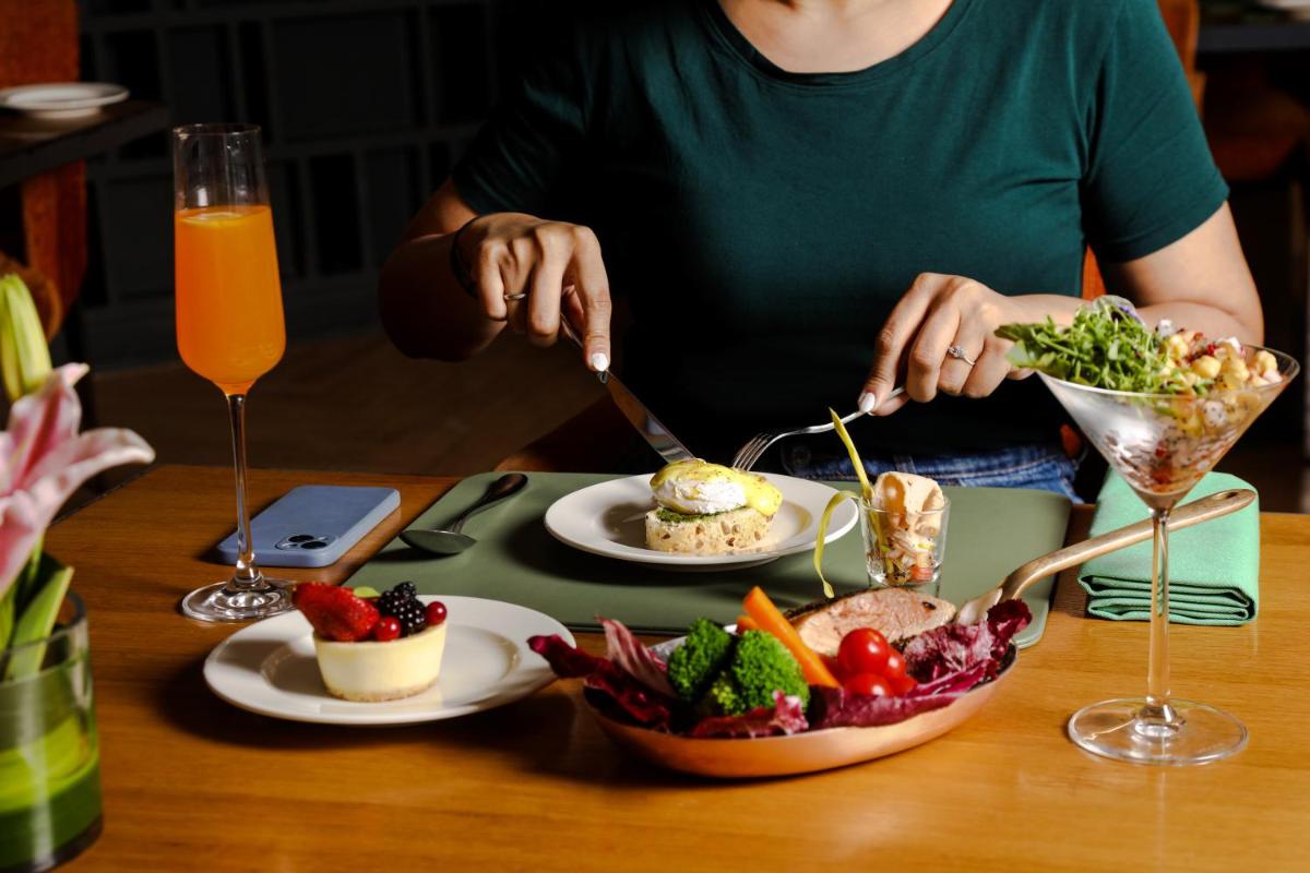a person eating food on a table with plates of food at The Westin Mumbai Powai Lake in Mumbai