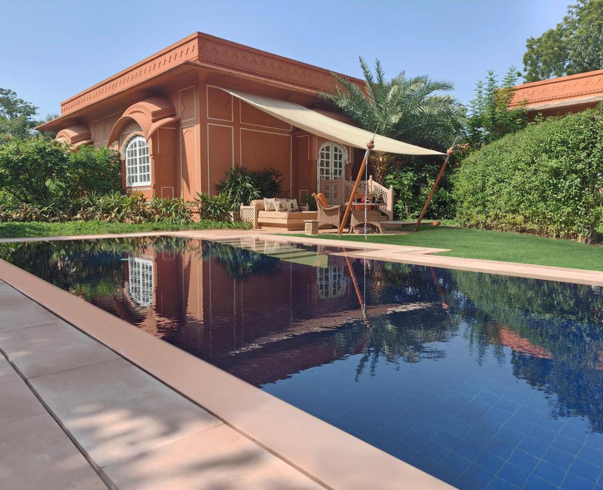 a swimming pool in front of a house at The Oberoi Rajvilas Jaipur in Jaipur