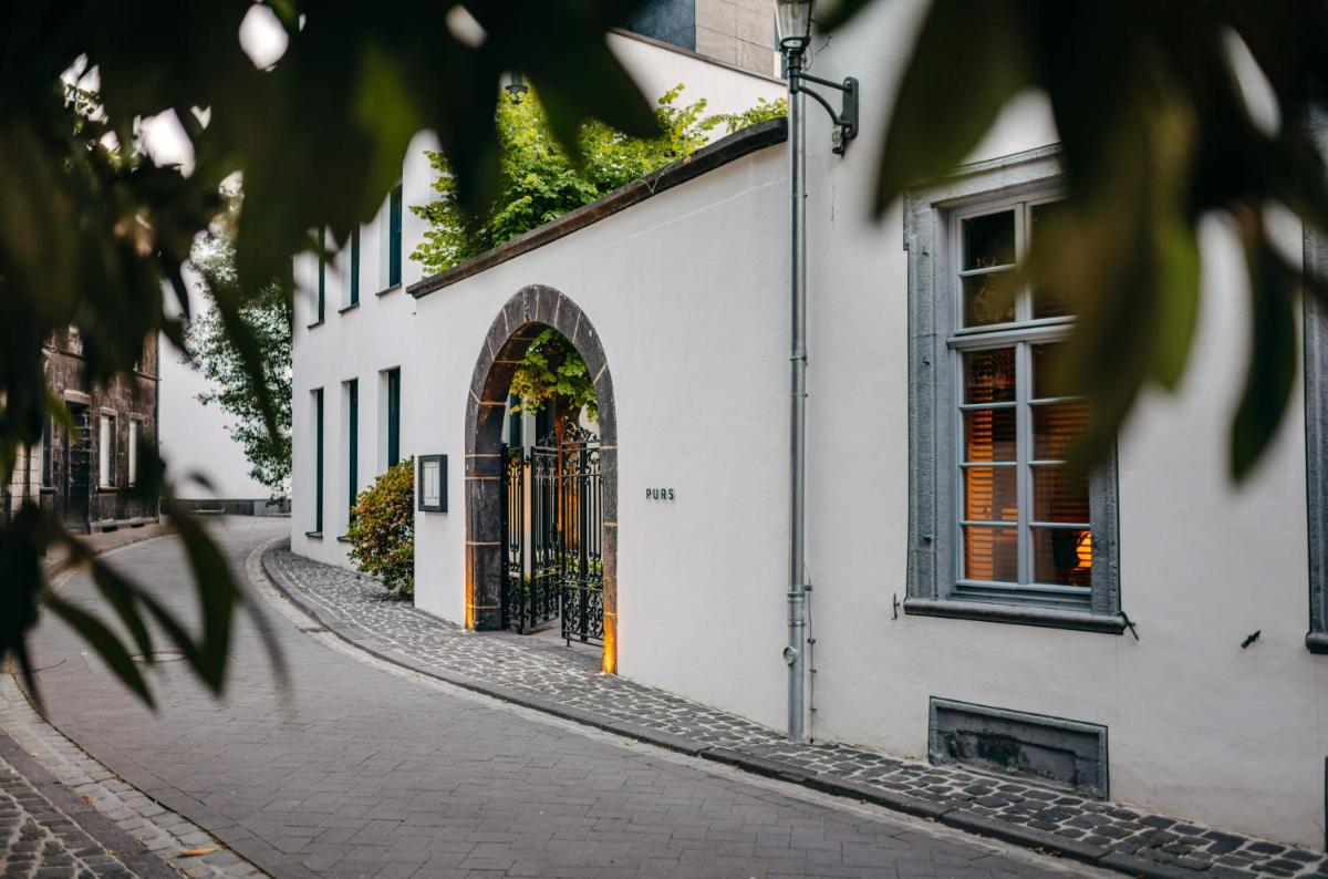 eine Kopfsteinpflasterstraße vor einem weißen Gebäude in der Unterkunft Hotel PURS in Andernach