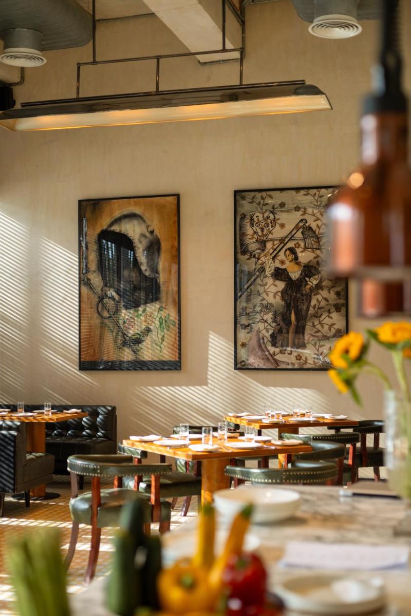 a restaurant with wooden tables and paintings on the wall at Grand Hyatt Gurgaon in Gurgaon