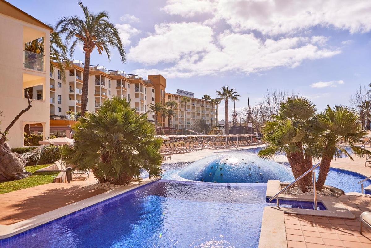 un complejo con piscina con palmeras y edificios en Zafiro Tropic, en Puerto de Alcudia