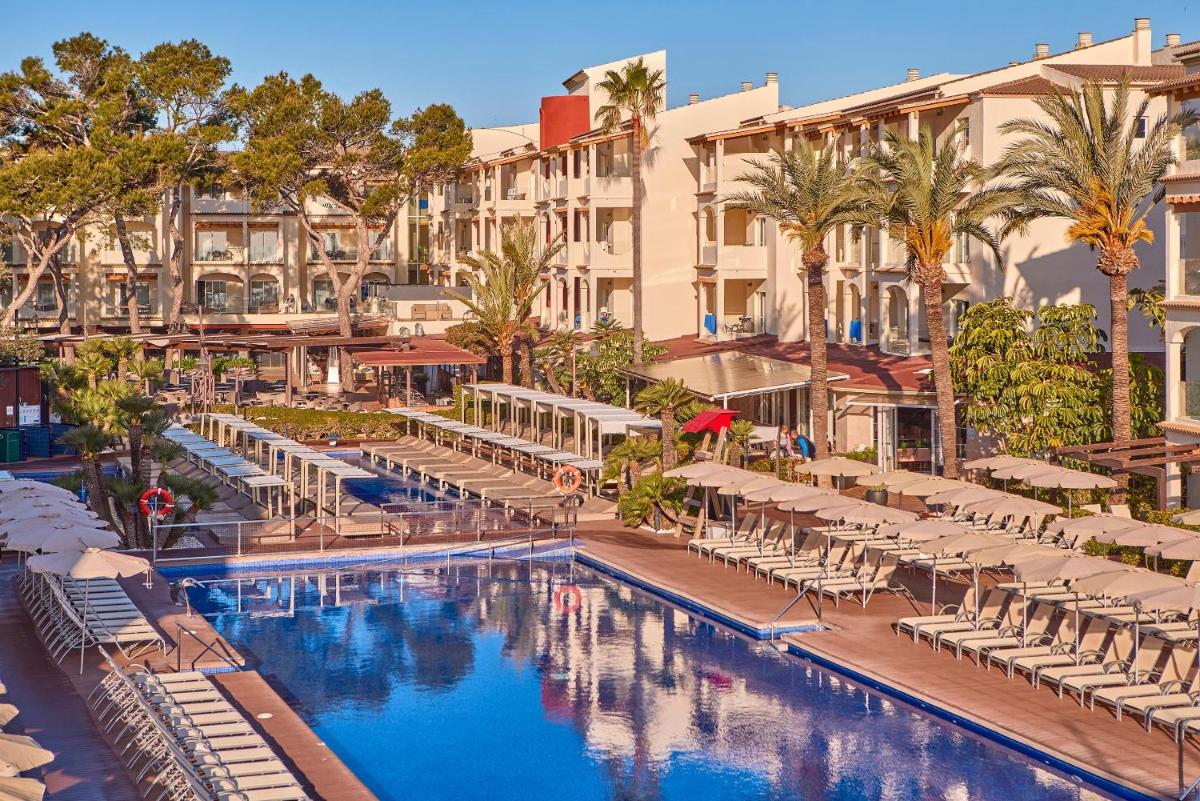 un hotel con piscina, sillas y edificios en Zafiro Bahia, en Playa de Muro