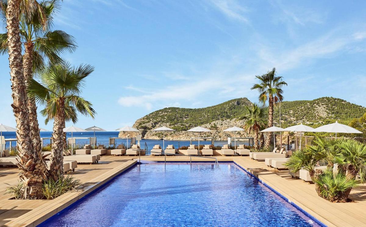 una piscina con tumbonas y sombrillas en un complejo en Zafiro Palace Andratx, en Camp de Mar