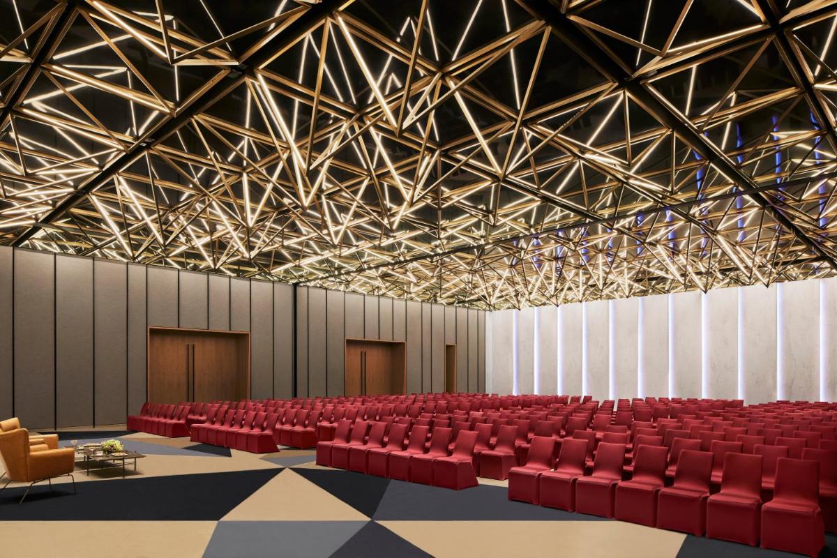 an empty auditorium with red chairs and ceilings at Taj The Trees, Mumbai in Mumbai