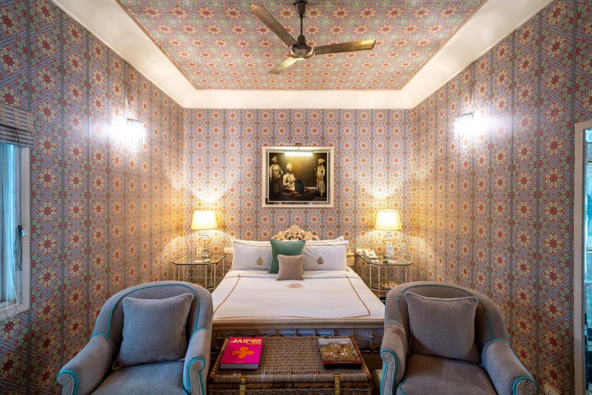 a bedroom with a bed and two chairs at Rajmahal Palace RAAS in Jaipur