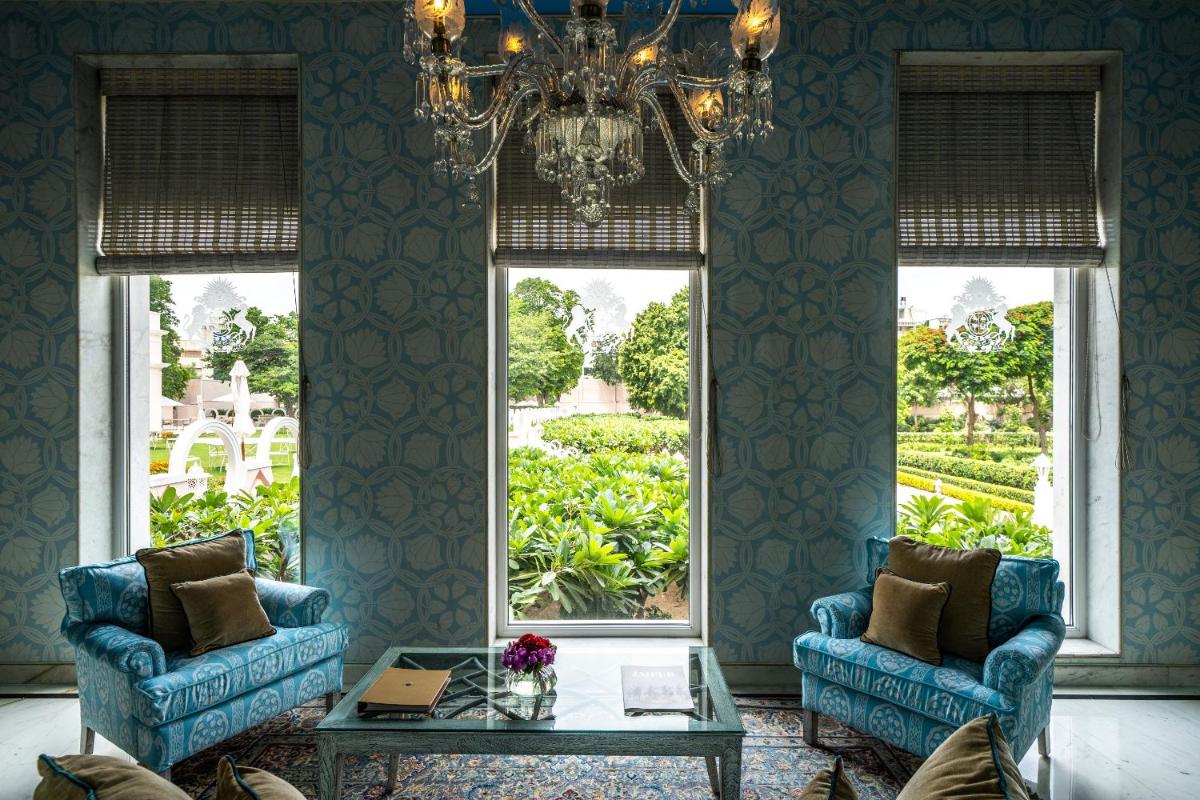 a living room with two blue chairs and a chandelier at Rajmahal Palace RAAS in Jaipur