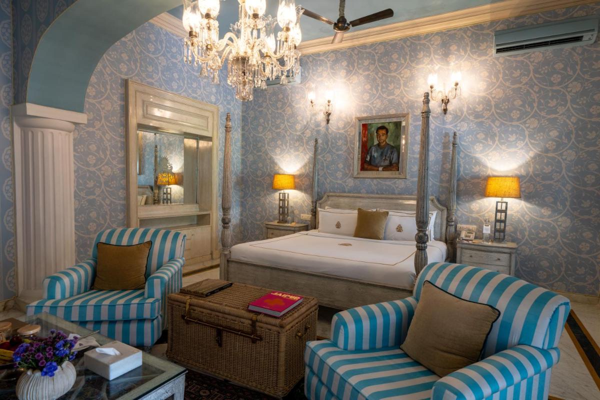 a bedroom with a bed and two chairs and a table at Rajmahal Palace RAAS in Jaipur