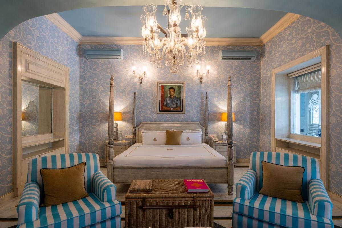 a bedroom with a bed and two chairs and a chandelier at Rajmahal Palace RAAS in Jaipur
