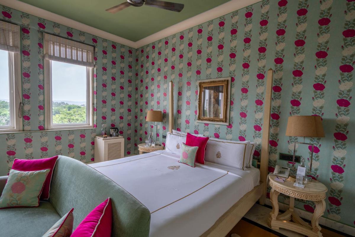 a bedroom with a large white bed with pink flowers at Rajmahal Palace RAAS in Jaipur