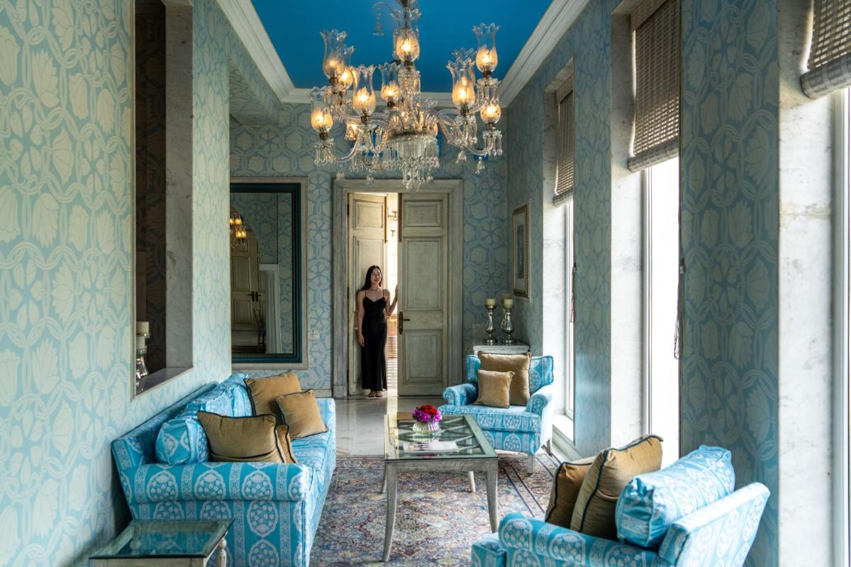 a woman standing in a room with blue furniture at Rajmahal Palace RAAS in Jaipur