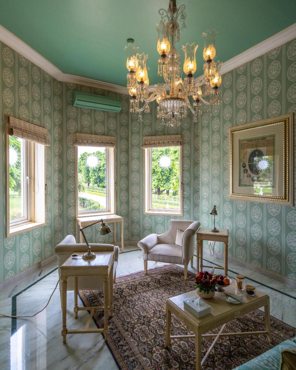 a living room with green walls and a chandelier at Rajmahal Palace RAAS in Jaipur