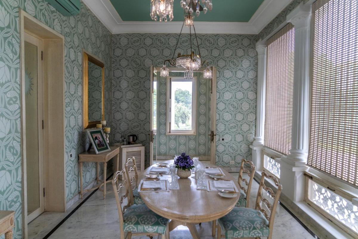 a dining room with a wooden table and chairs at Rajmahal Palace RAAS in Jaipur