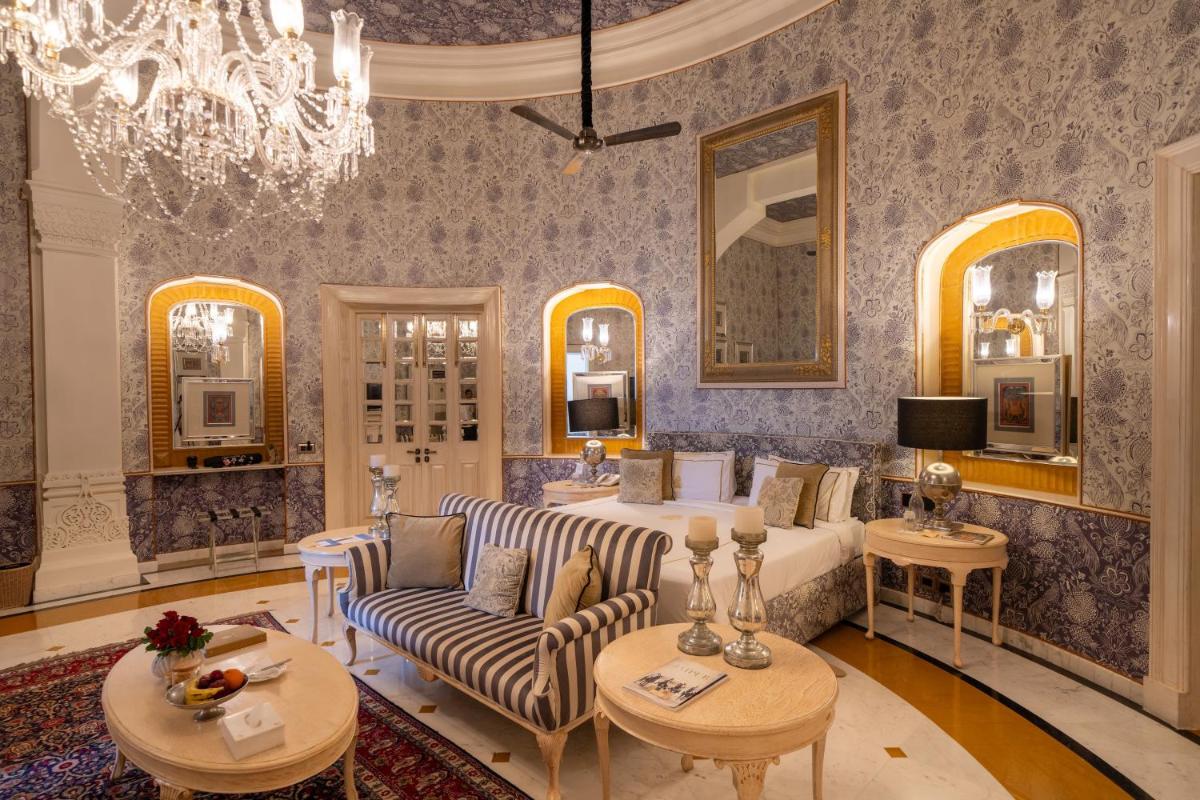 a bedroom with a bed and a couch and a chandelier at Rajmahal Palace RAAS in Jaipur