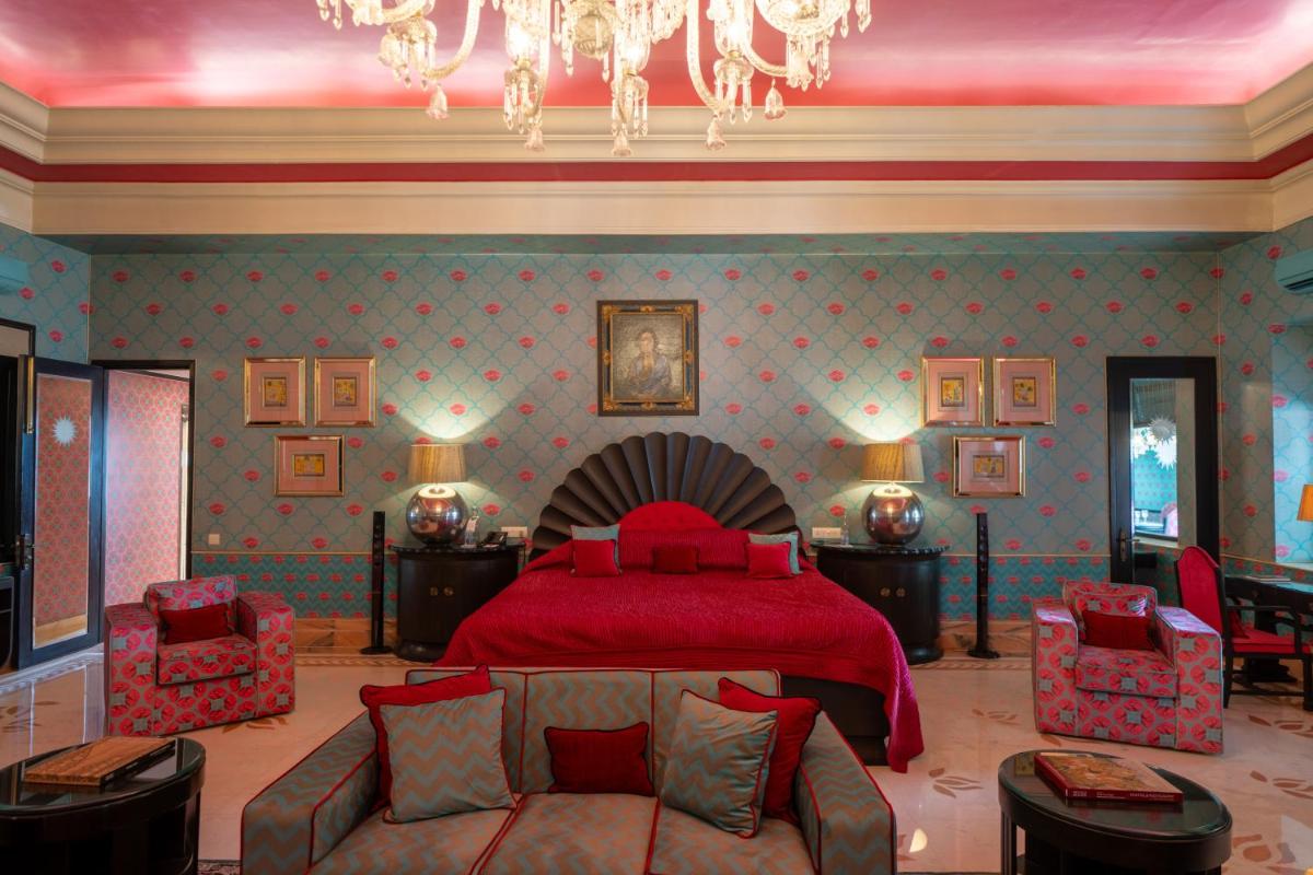 a bedroom with a red bed and a couch at Rajmahal Palace RAAS in Jaipur