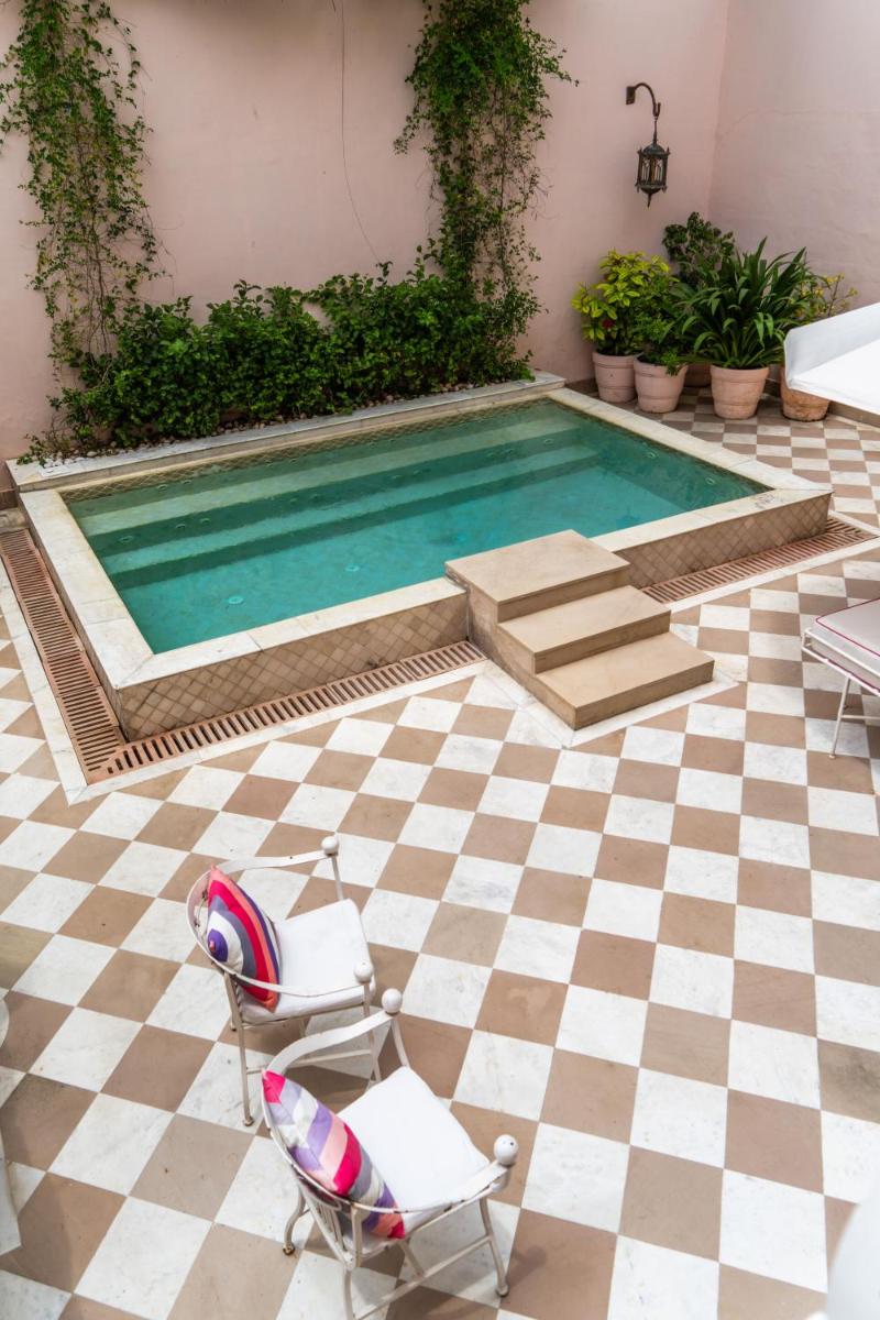 a swimming pool with a pair of chairs and a table at Rajmahal Palace RAAS in Jaipur