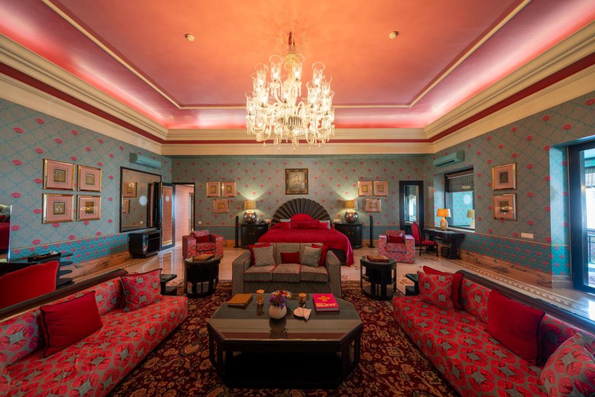 a living room with red furniture and a chandelier at Rajmahal Palace RAAS in Jaipur