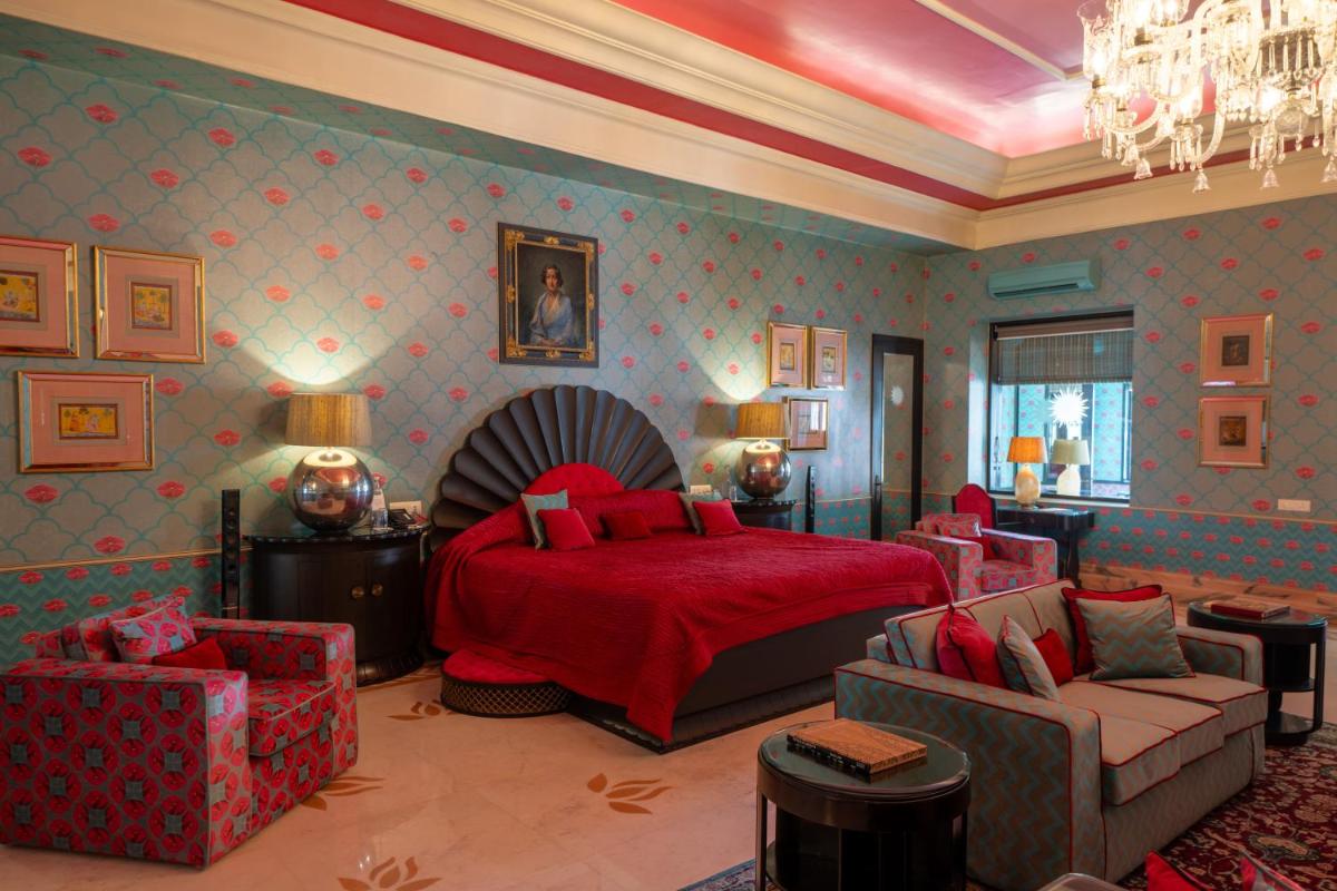 a bedroom with a red bed and a couch and chairs at Rajmahal Palace RAAS in Jaipur