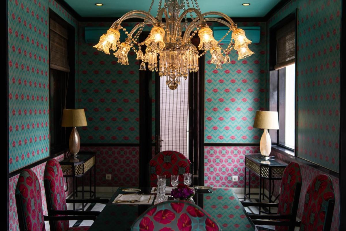 a dining room with a chandelier and a table and chairs at Rajmahal Palace RAAS in Jaipur