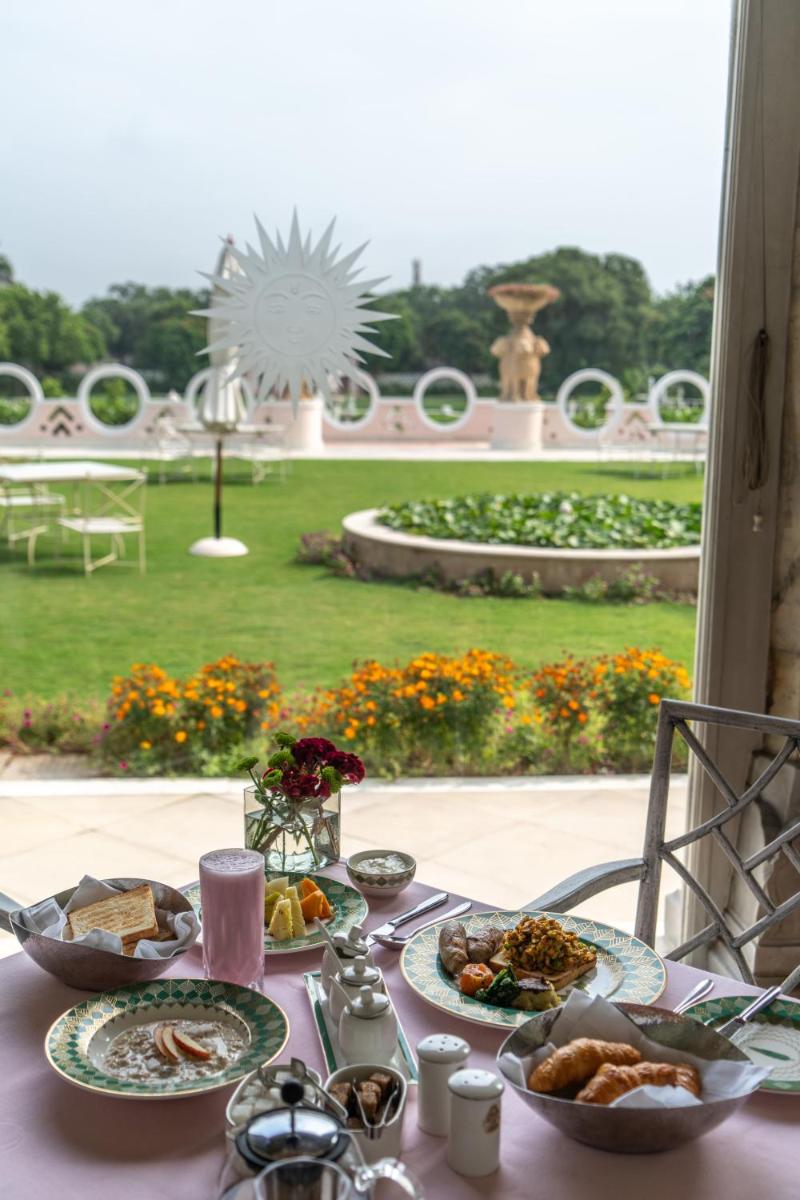 a table with plates of food and a view of a garden at Rajmahal Palace RAAS in Jaipur