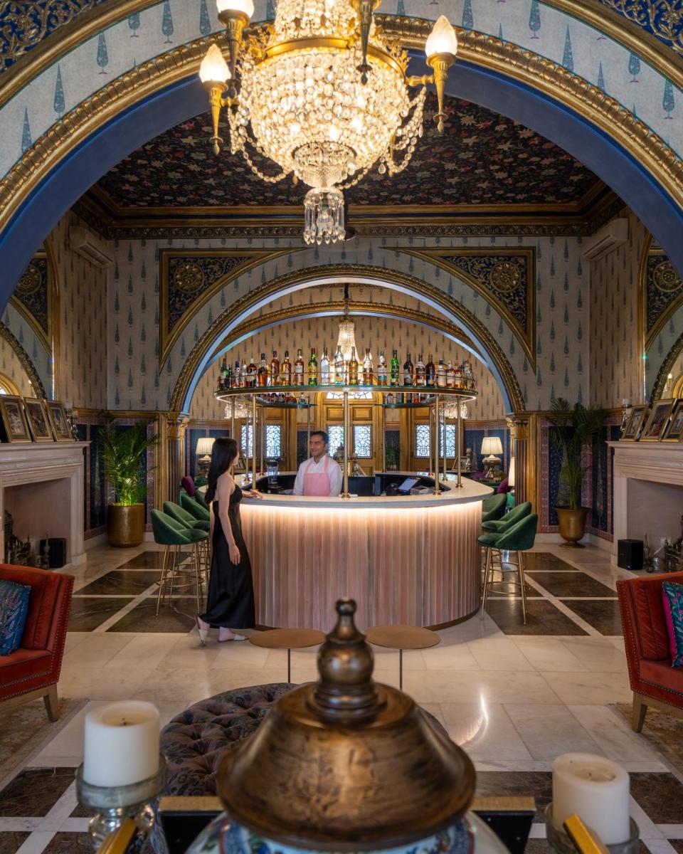 a man and woman standing at a bar in a hotel lobby at Rajmahal Palace RAAS in Jaipur