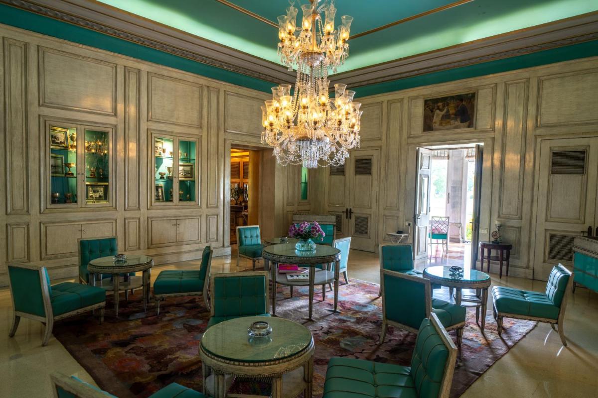 a dining room with tables and chairs and a chandelier at Rajmahal Palace RAAS in Jaipur