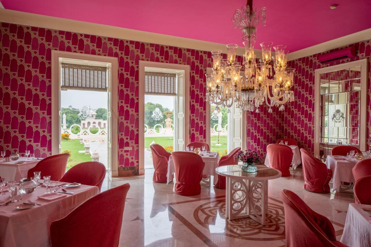 a dining room with pink walls and tables and chairs at Rajmahal Palace RAAS in Jaipur
