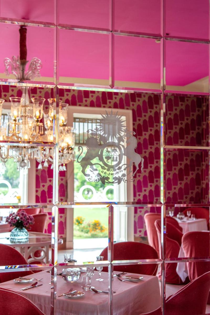 a dining room with pink walls and tables and chairs at Rajmahal Palace RAAS in Jaipur