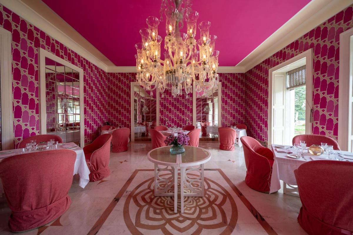 a dining room with pink walls and a chandelier at Rajmahal Palace RAAS in Jaipur
