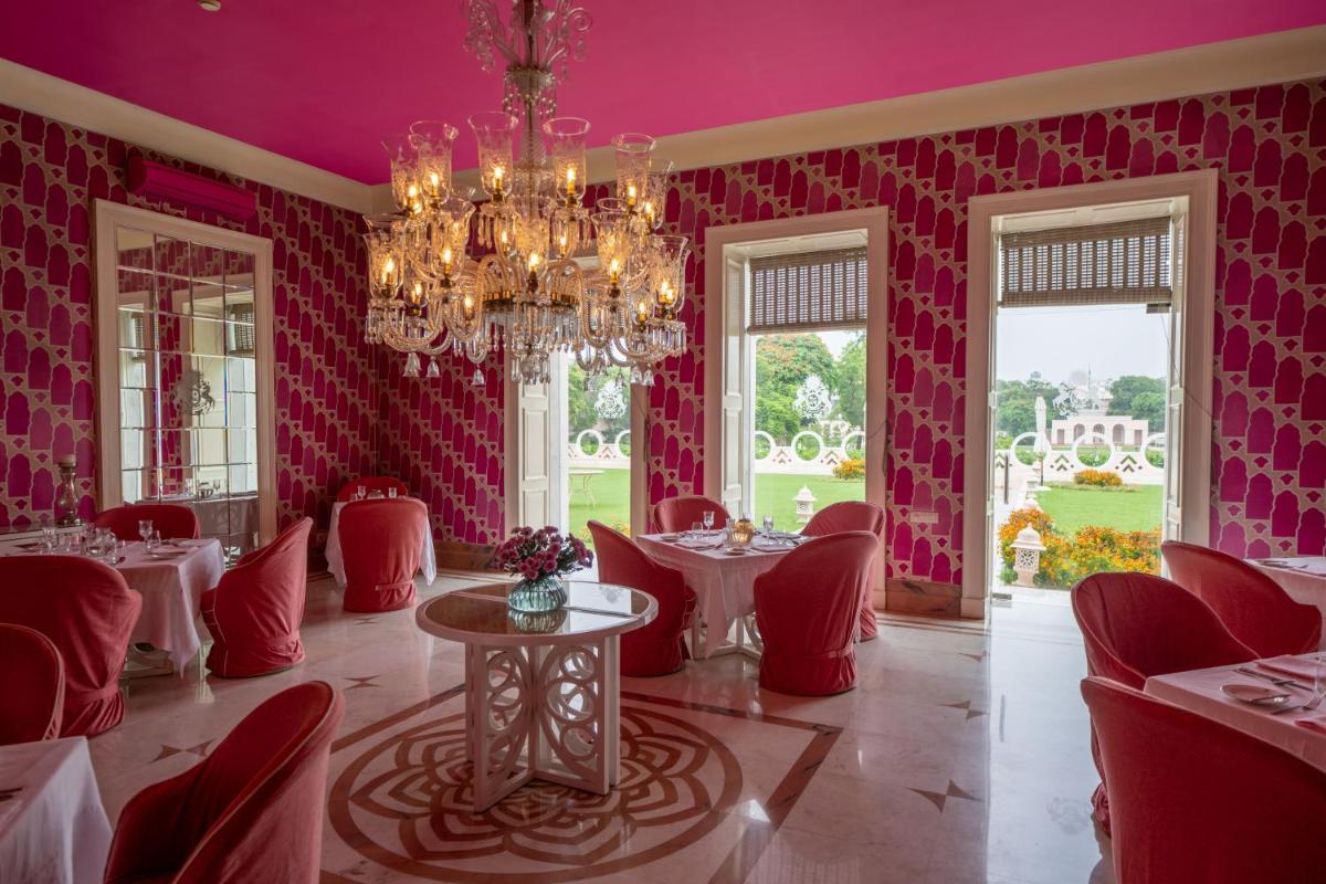 a dining room with red walls and a chandelier at Rajmahal Palace RAAS in Jaipur
