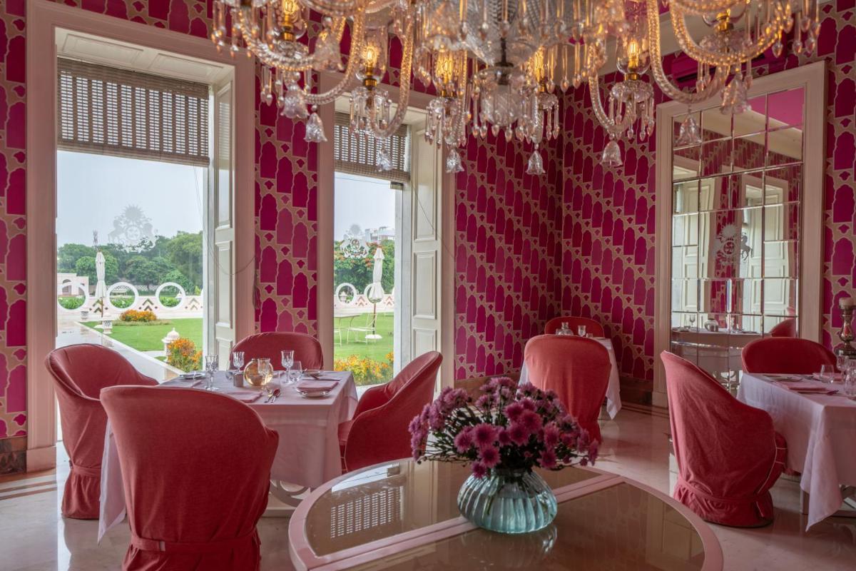 a dining room with tables and chairs and a chandelier at Rajmahal Palace RAAS in Jaipur