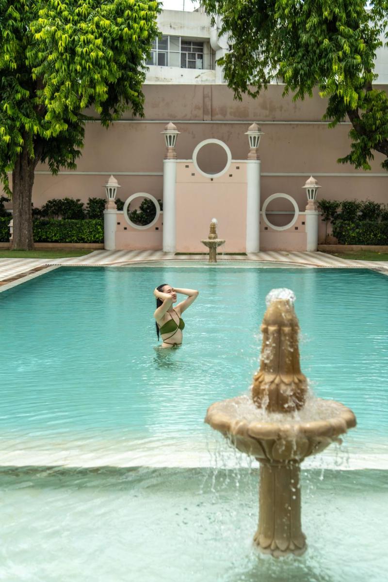 a woman swimming in a fountain in a swimming pool at Rajmahal Palace RAAS in Jaipur