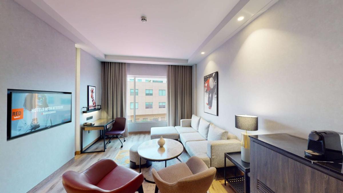 a living room with a couch and a table and chairs at Radisson RED Chandigarh Mohali in Chandīgarh