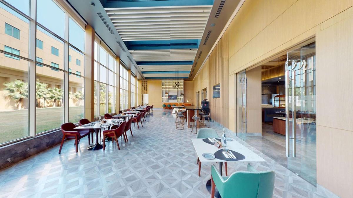 a dining room with tables and chairs and windows at Radisson RED Chandigarh Mohali in Chandīgarh