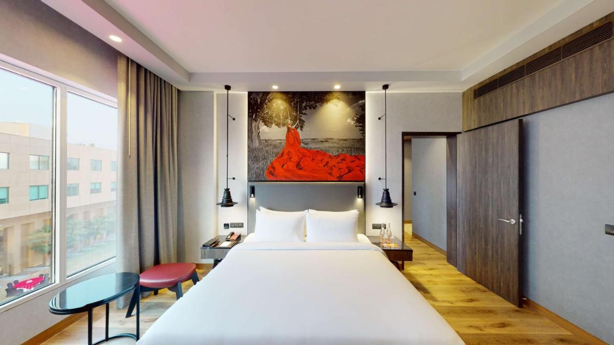 a bedroom with a large bed and a large window at Radisson RED Chandigarh Mohali in Chandīgarh