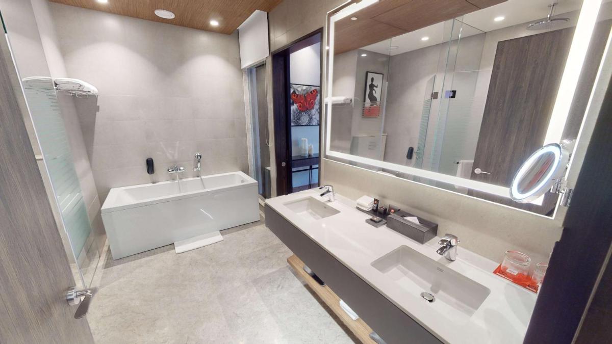 a bathroom with two sinks and a tub and a mirror at Radisson RED Chandigarh Mohali in Chandīgarh