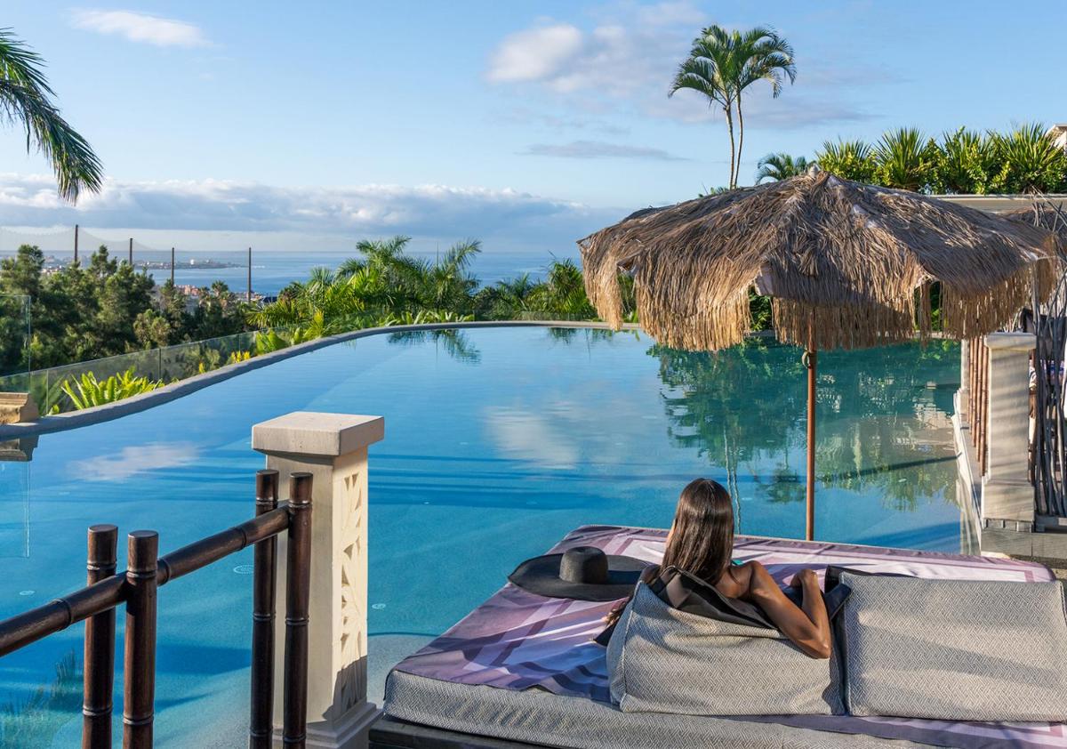 una mujer acostada en una cama junto a una piscina en Royal River, Luxury Hotel - Adults Only, en Adeje