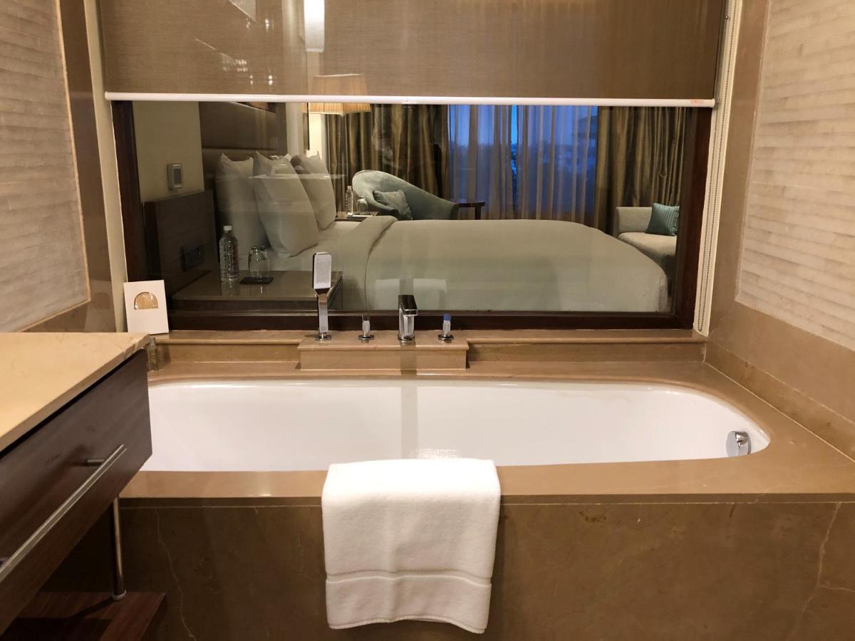 a bathroom with a bath tub with a bed in a mirror at DoubleTree by Hilton Agra in Agra