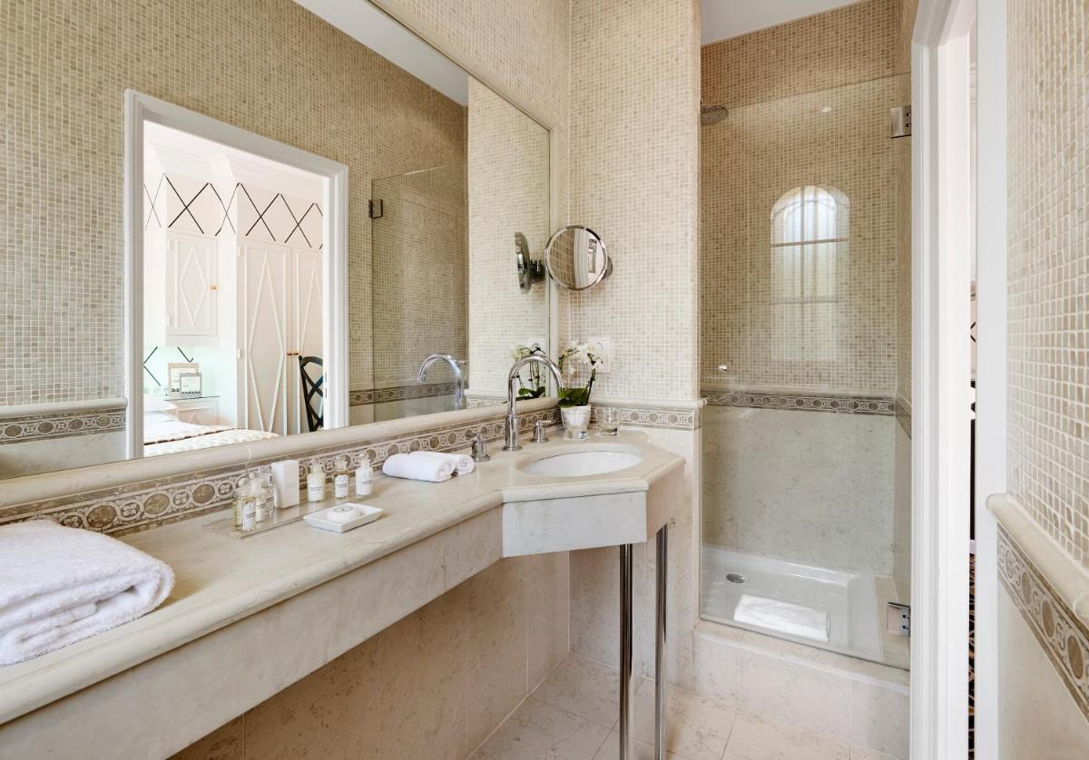 une salle de bains avec lavabo, miroir et douche dans l'établissement Hôtel Belles Rives, à Juan-les-Pins