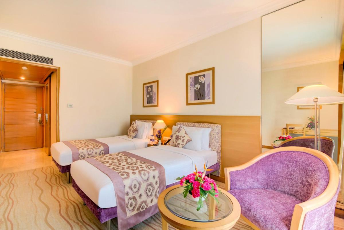 a hotel room with two beds and a purple chair at Accord Puducherry in Puducherry