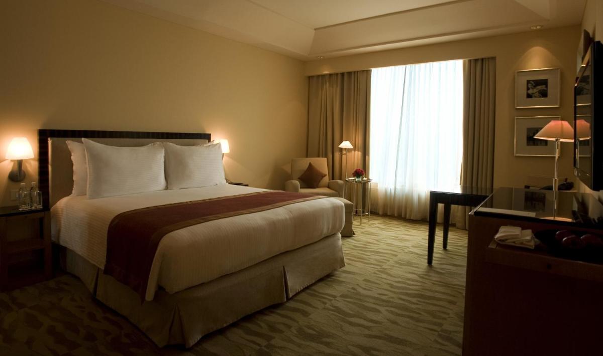 a hotel room with a bed and a window at The Grand New Delhi in New Delhi a hotel room with a bed and a window at The Grand New Delhi in New Delhi