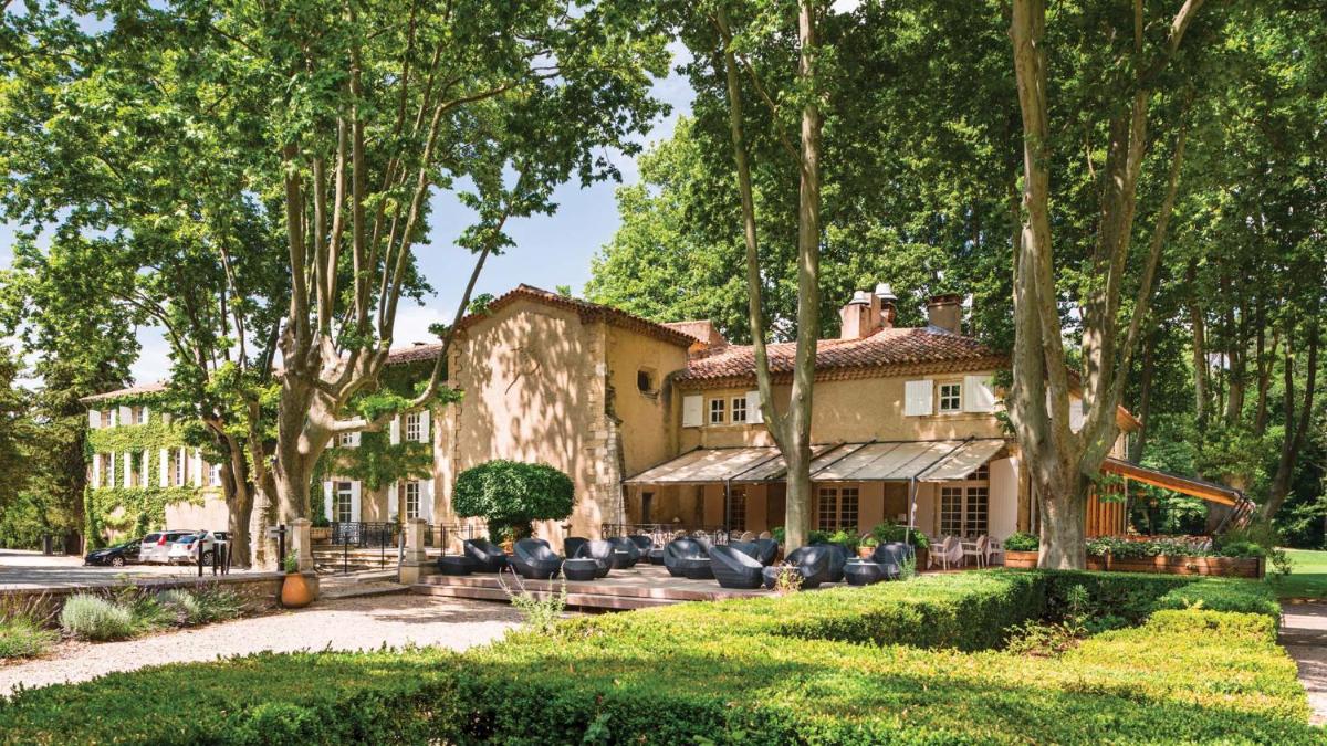 une vue extérieure d'une maison avec des arbres dans l'établissement Moulin de Vernègues Hôtel & Spa, à Mallemort