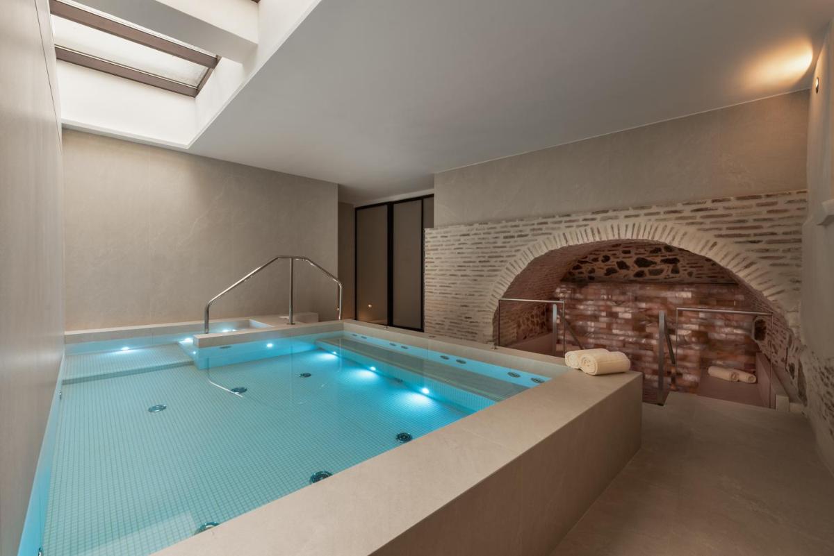 una gran piscina en una habitación con una pared de ladrillo en Áurea Toledo by Eurostars Hotel company, en Toledo