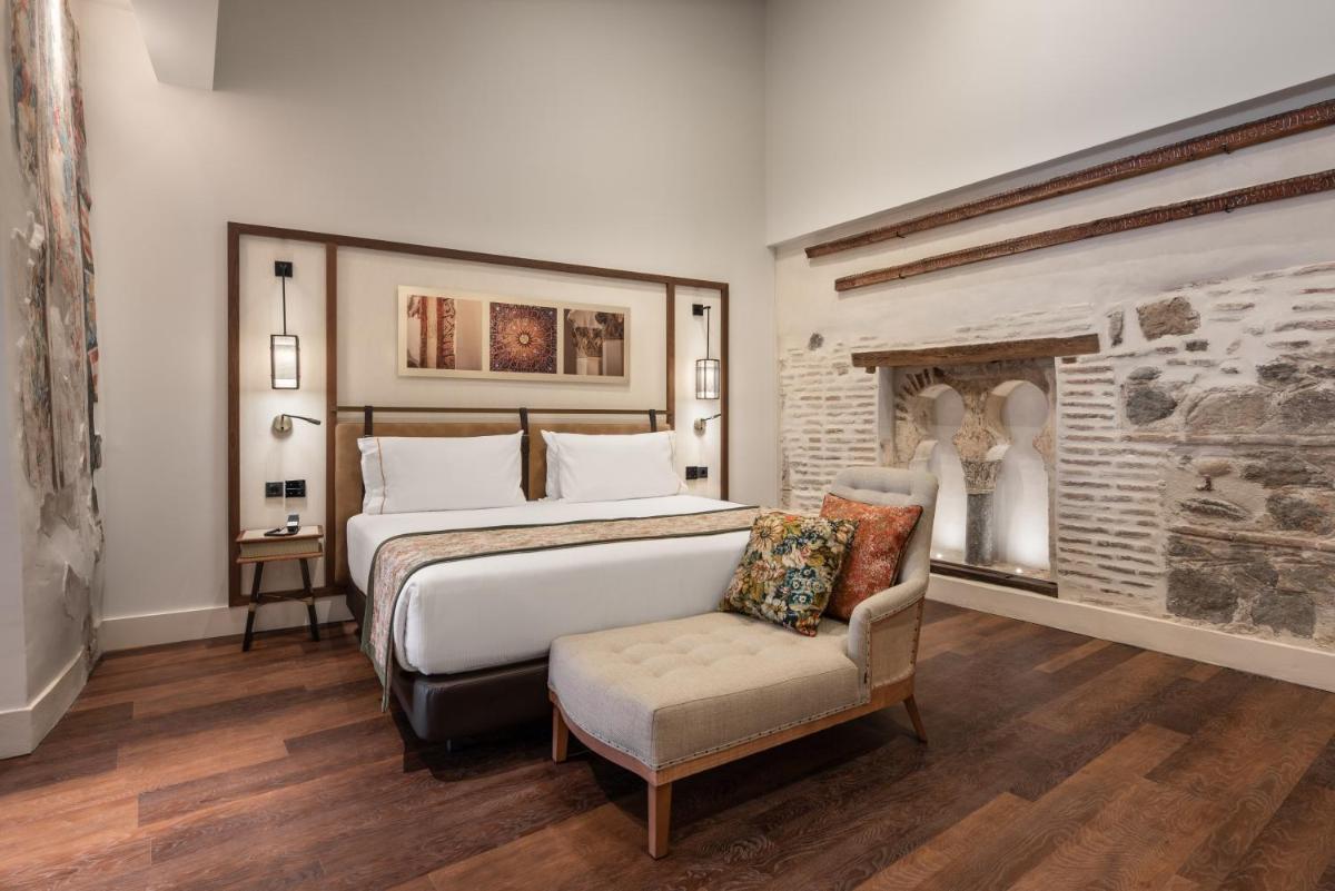 Un dormitorio con una cama grande y una silla. en Áurea Toledo by Eurostars Hotel company, en Toledo