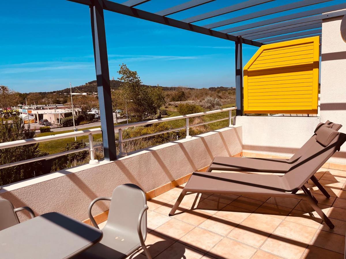 un groupe de chaises sur un balcon avec vue dans l'établissement Résidence Hôtelière Natureva & Spa, au Cap d'Agde