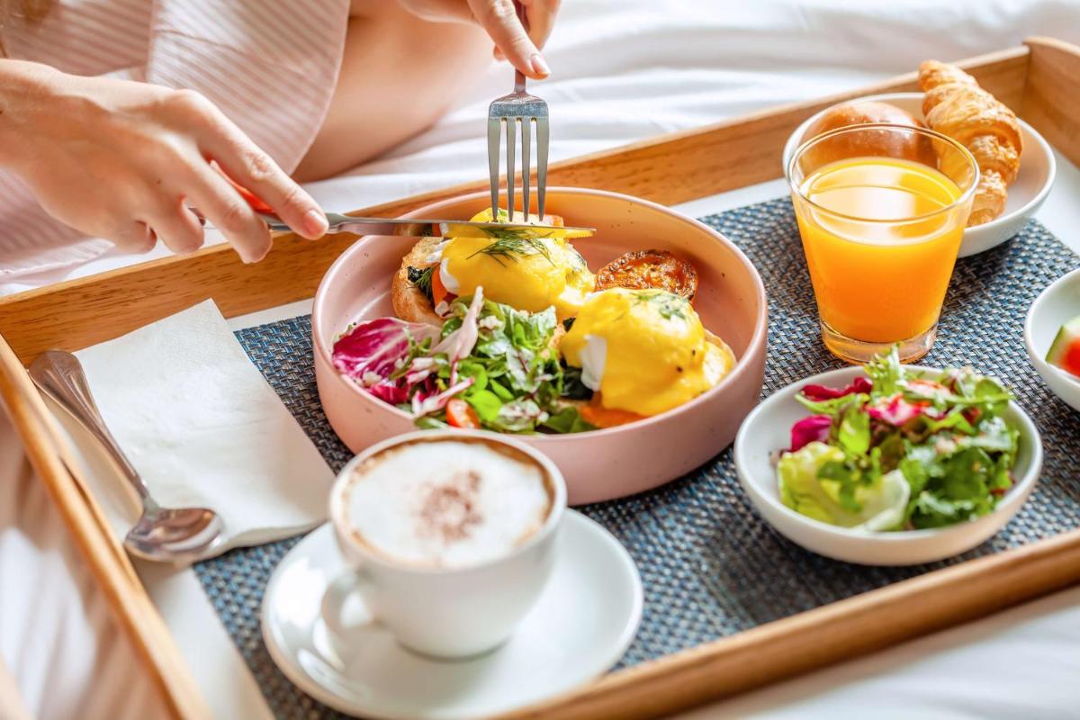 a tray with a plate of food and a woman eating food at Radisson Hyderabad Hitec City in Hyderabad