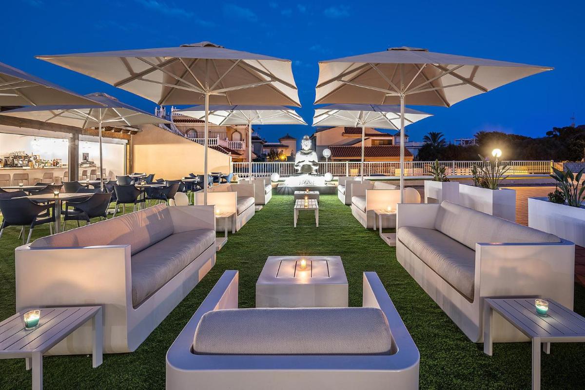 Un patio en la azotea con sofás, mesas y sombrillas. en Poseidon La Manga Hotel & Spa - Designed for Adults, en La Manga del Mar Menor