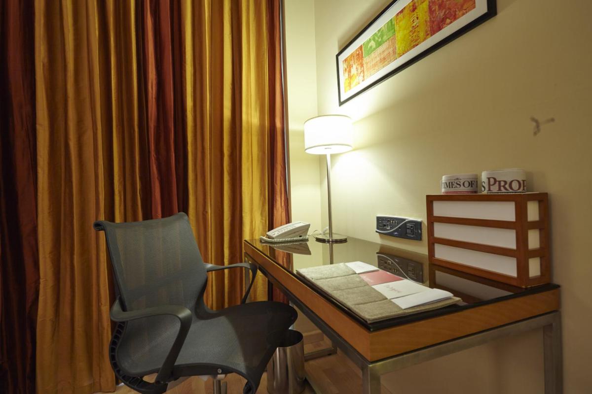 a room with a desk with a chair and a lamp at Turyaa Chennai - OMR IT Expressway in Chennai
