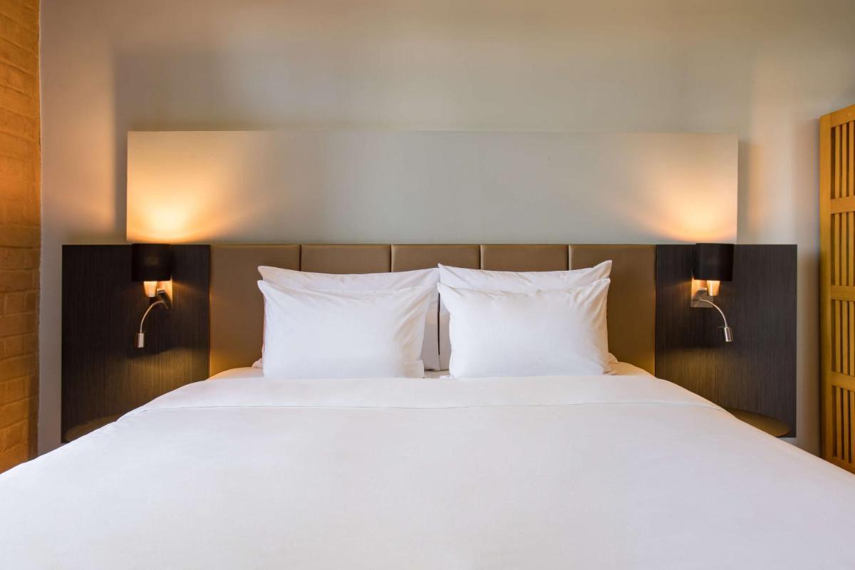 a large bed with white sheets and two pillows at Radisson Blu Plaza Delhi Airport in New Delhi a large bed with white sheets and two pillows at Radisson Blu Plaza Delhi Airport in New Delhi