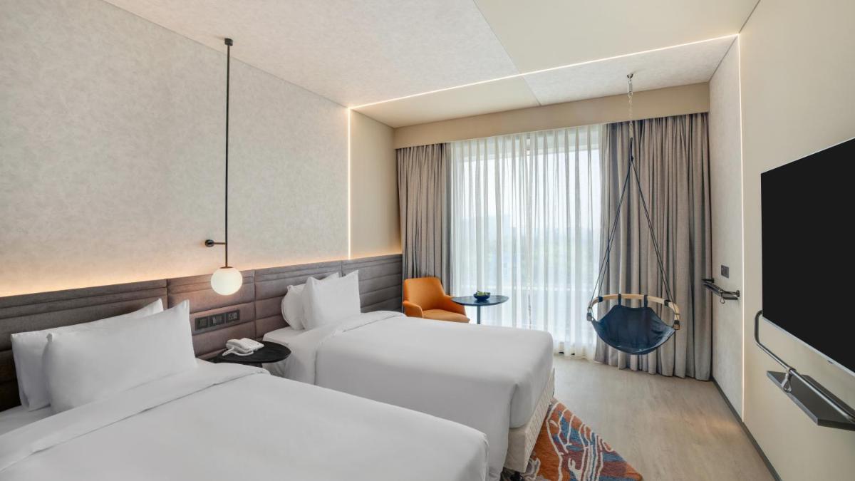 a hotel room with two beds and a tv at Novotel Pune Viman Nagar Road in Pune