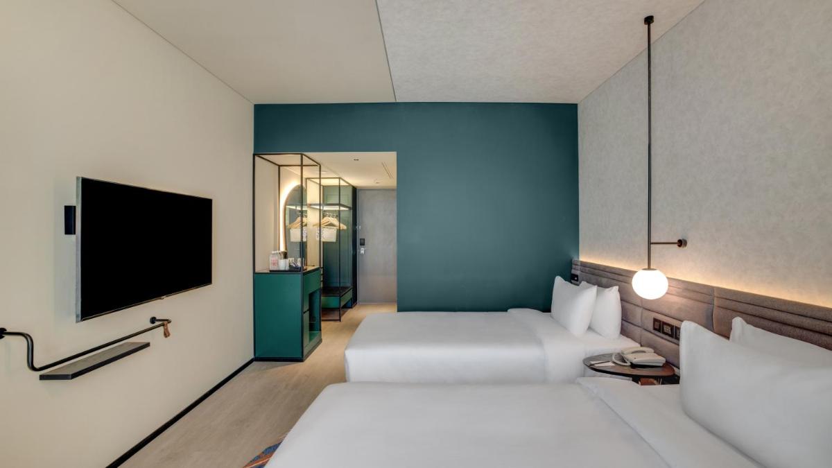 a hotel room with two beds and a flat screen tv at Novotel Pune Viman Nagar Road in Pune